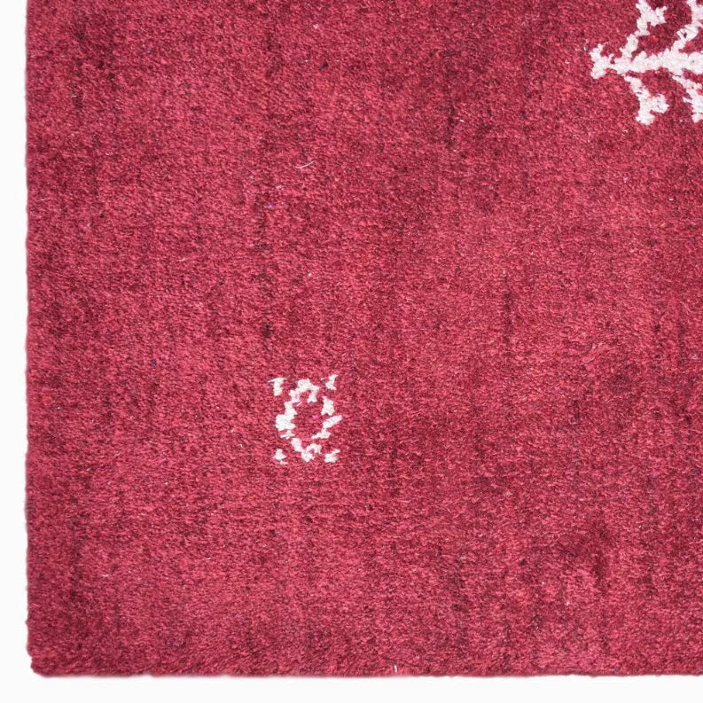 Red maroon area rug close-up with white small motifs and dense looped pile texture