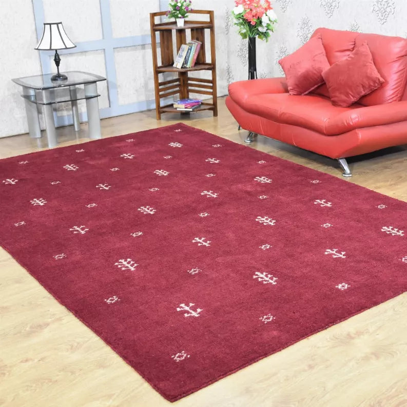 Burgundy patterned area rug with repeating small white geometric motifs, angled view