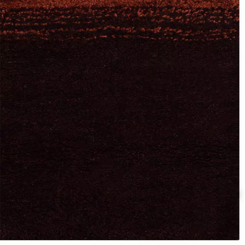 Close-up of dark brown rug pile with fine speckling and faint red highlights