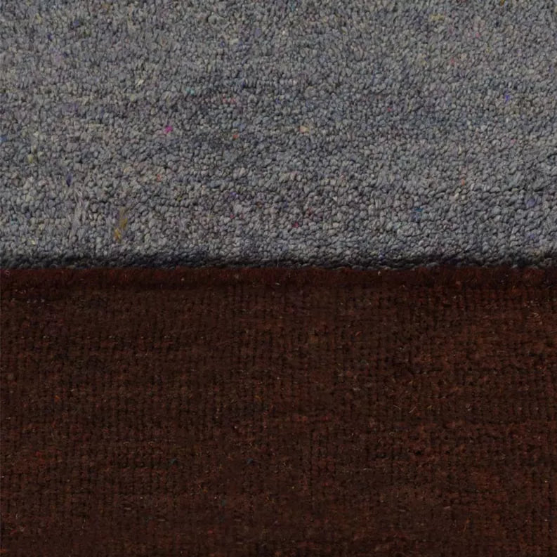 Close-up of rug edge showing gray pile and dark brown underside with rust band
