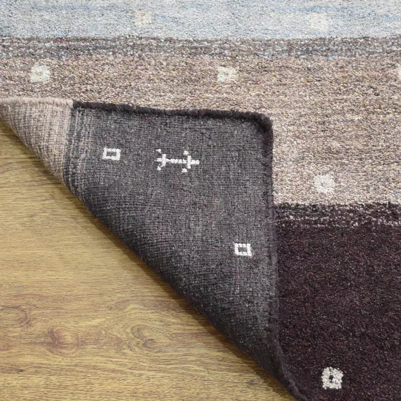 Hand-knotted area rug with dark charcoal field, cream geometric motifs, and border strip.