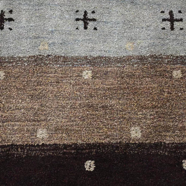 Close-up of area rug texture: gray field, brown panel, dark border with tiny cross motifs