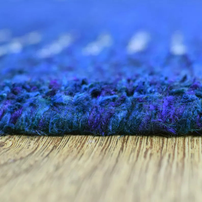 Blue rug edge close-up with textured shag pile and light wood floor
