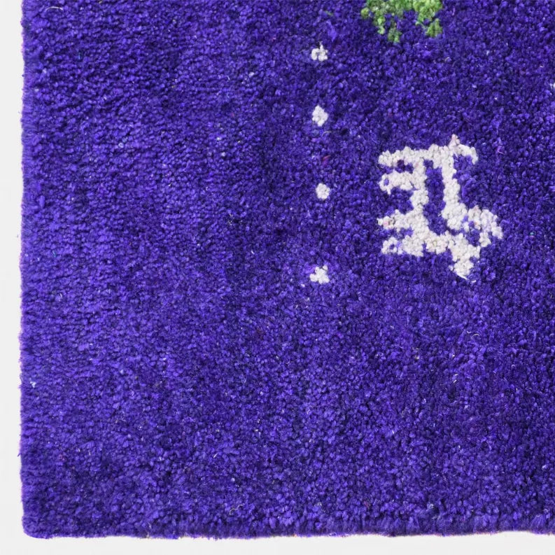 Purple area rug with white, green, and yellow geometric pattern on textured pile