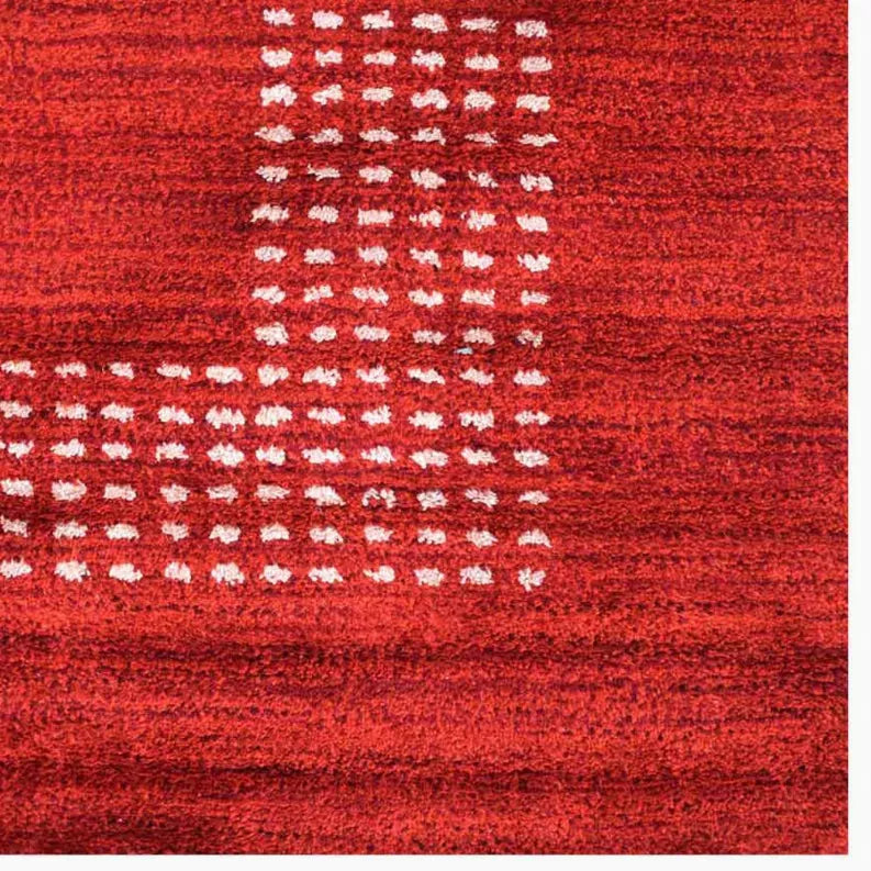 Close-up red area rug with white dotted grid pattern and textured weave