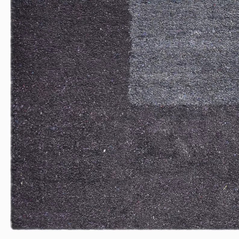 Charcoal and dark gray area rug with speckled woven texture, flat close-up view