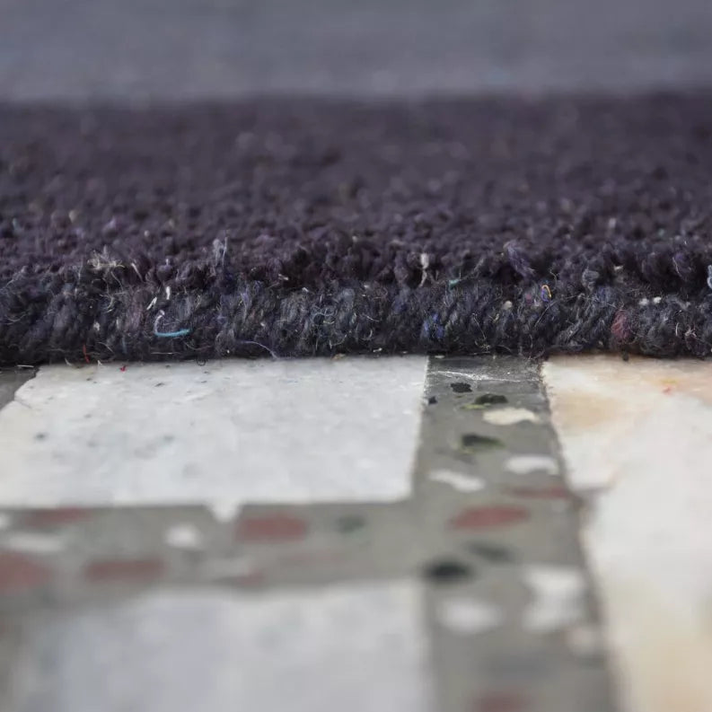 Dark gray area rug pile close-up with visible edge binding and speckled fibers