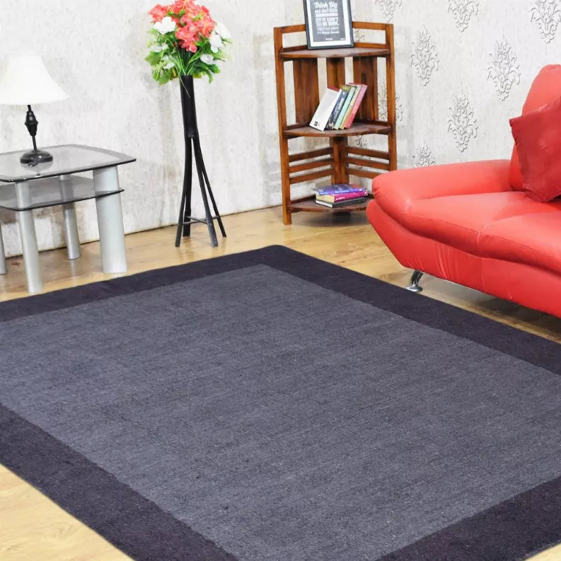 Dark gray area rug with darker border and lighter center, shown on floor in room