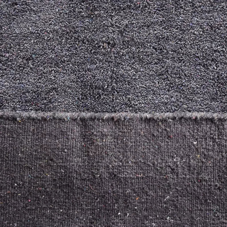 Dark gray area rug texture close-up with fringe and speckled yarn fibers