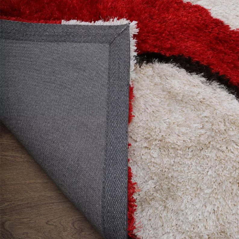 Shag area rug corner with gray backing panel and red-white textured pile