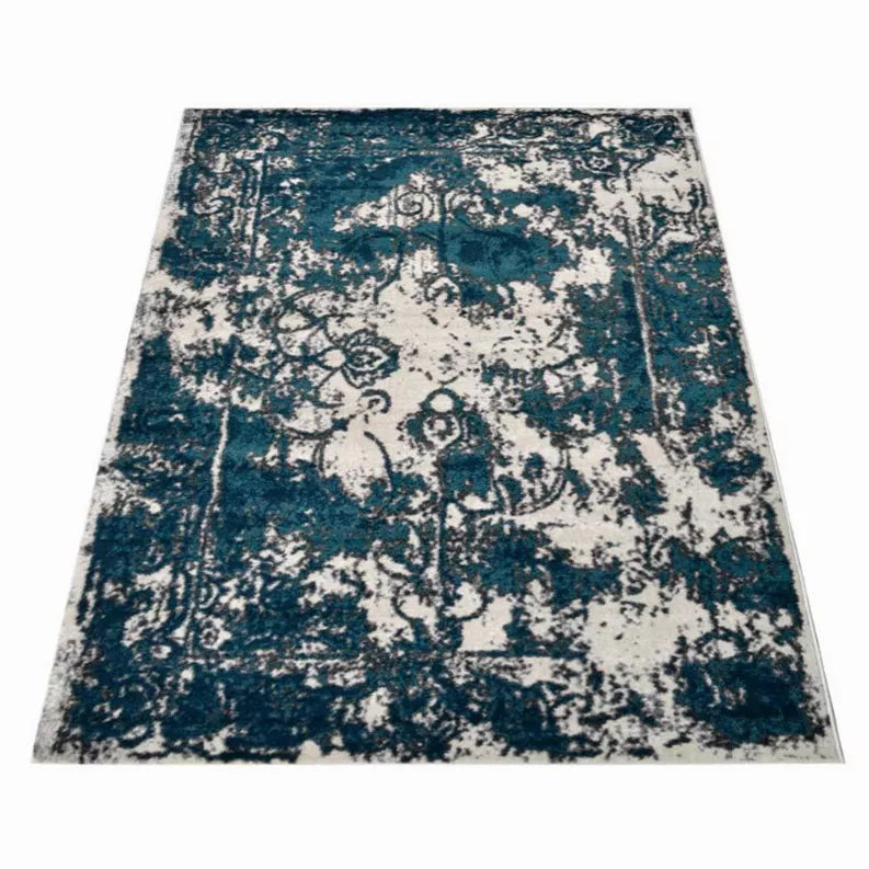Abstract area rug with teal blue and off-white distressed floral and scroll motifs