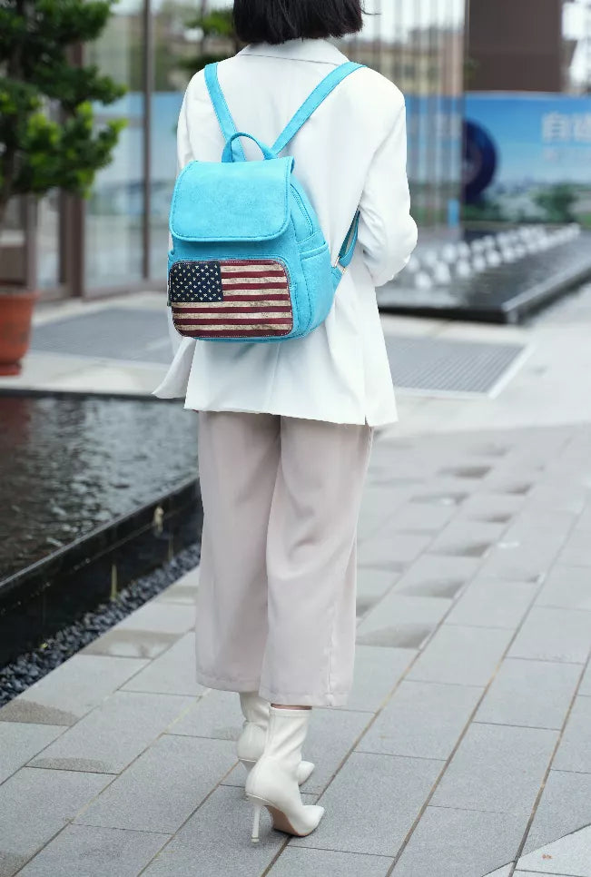 Turquoise mini backpack worn from the back, with blue straps and an American flag front pocket.