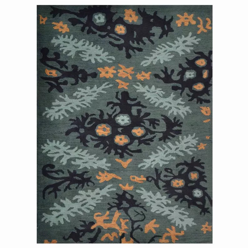 Hand-tufted wool area rug close-up, teal-gray floral foliage with navy and orange motifs