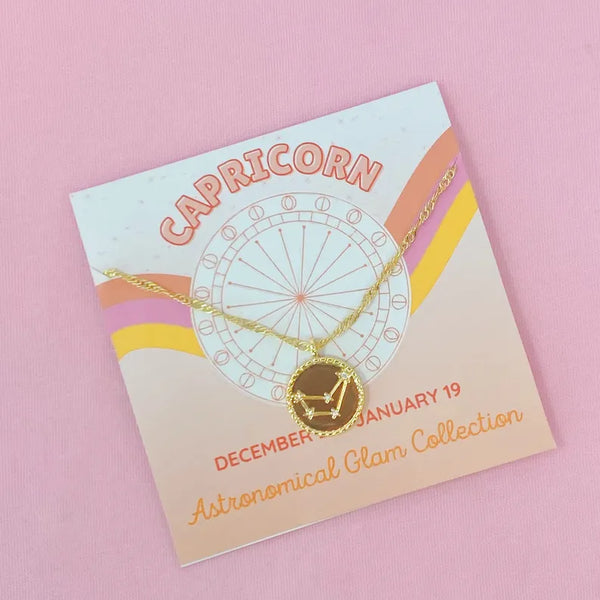 Capricorn zodiac charm necklace with gold chain on decorative display card