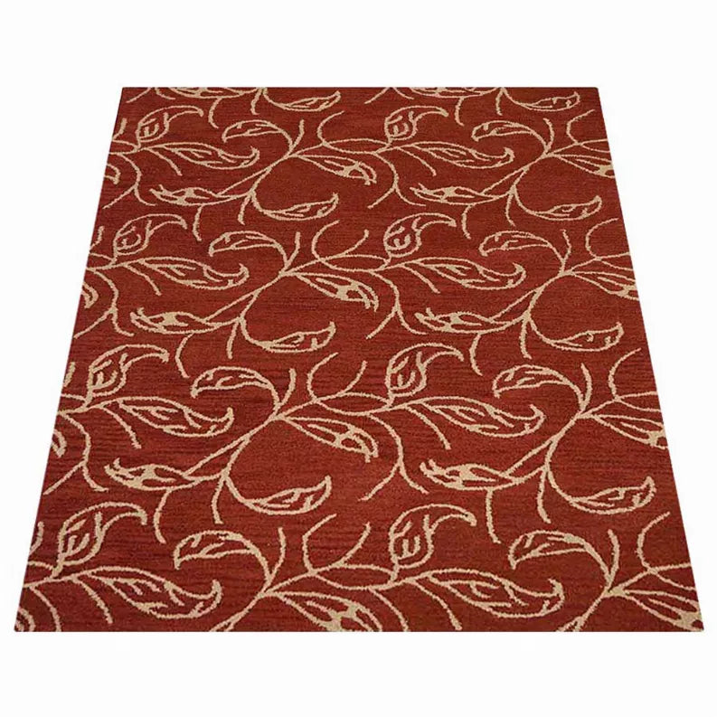 Rust red area rug with repeating cream bird-and-vine motif across the surface.