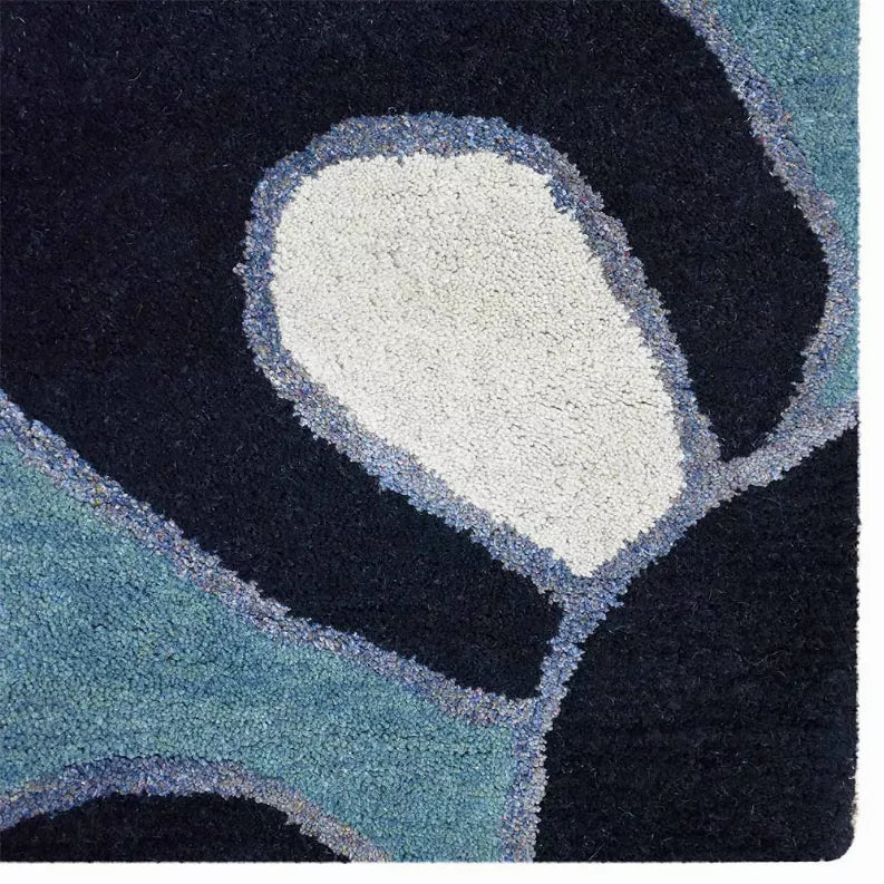 Close-up floral rug corner with dark navy petal shapes and pale blue background
