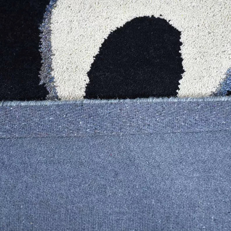 Close-up rug edge with tufted pile and outlined dark motif on blue base