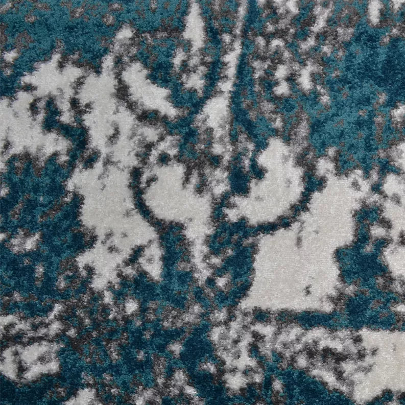 Abstract area rug with teal and blue distressed motifs over white ground