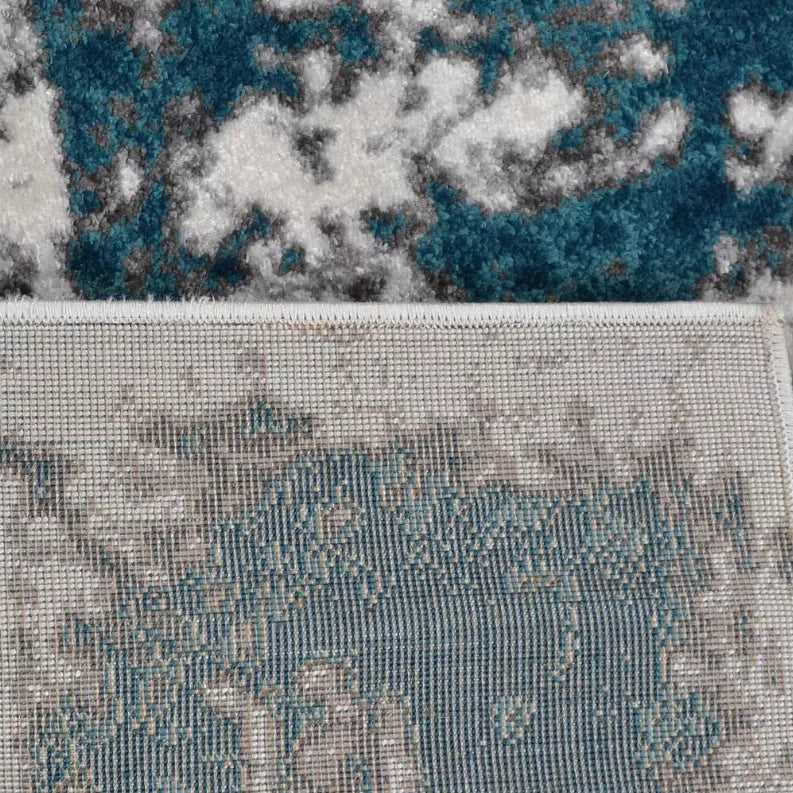 Abstract area rug border with teal-blue pattern and speckled white ground