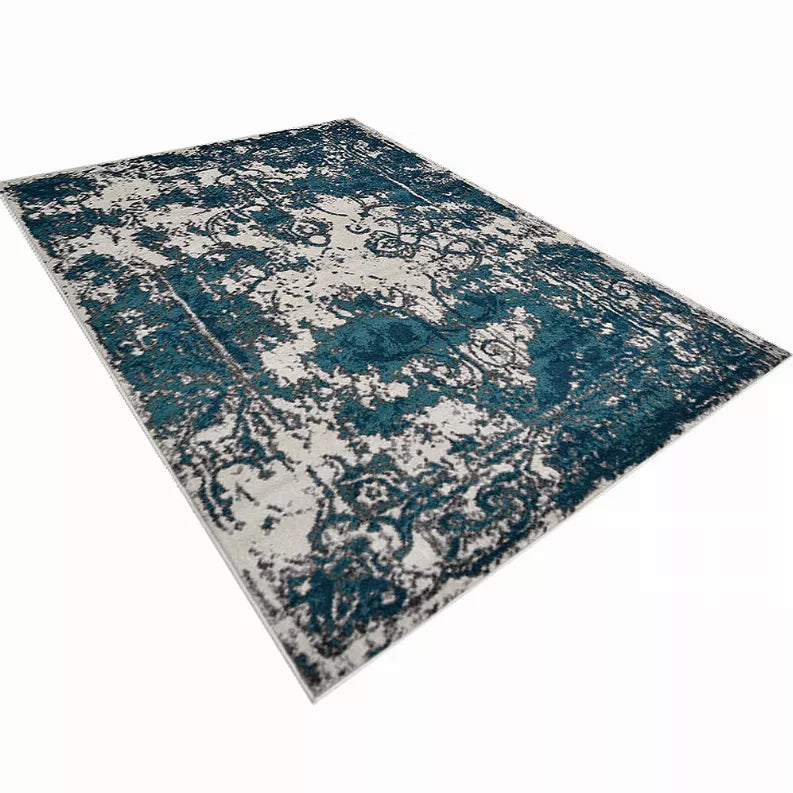 Abstract area rug angled view with teal and blue distressed medallion pattern