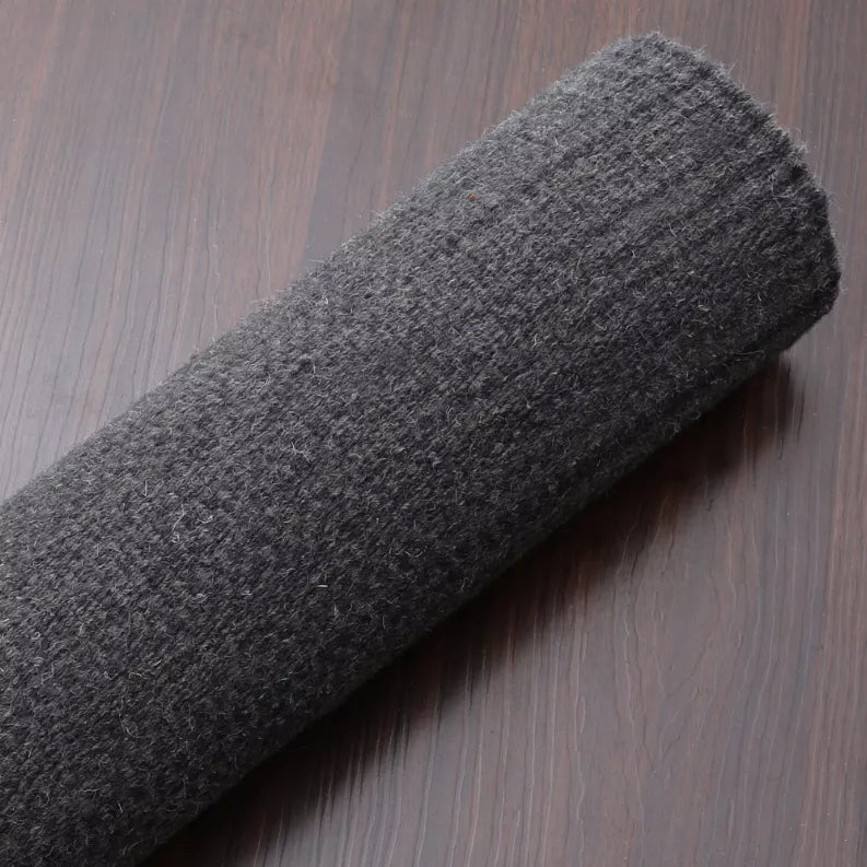 Rolled dark gray wool rug detail with compact flat woven surface