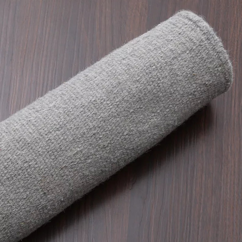 Rolled gray flatweave wool rug edge showing tight woven texture