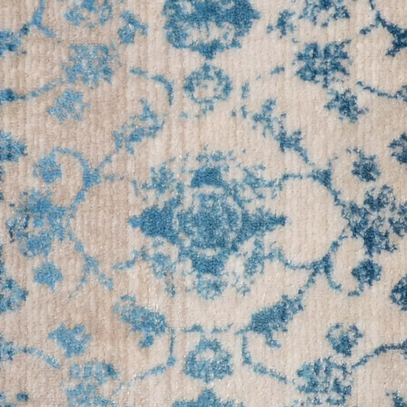 Close-up of blue floral motifs on a cream background rug with textured weave.