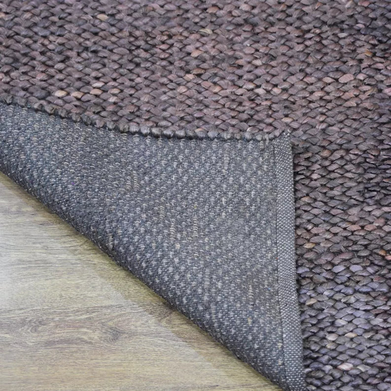 Hand-woven jute rug corner showing braided texture and gray fabric border edge