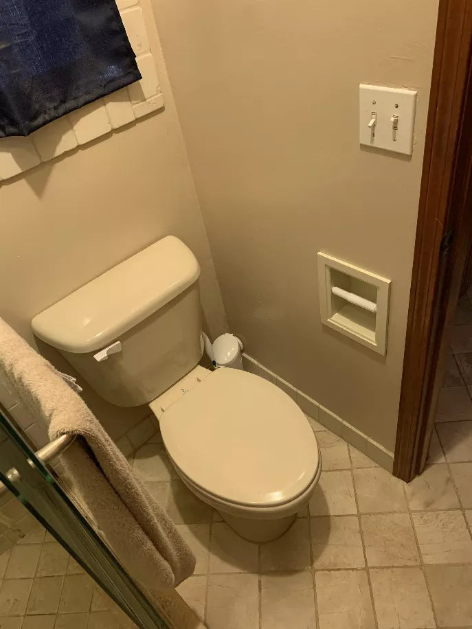 Recessed toilet paper holder with roll in light gray wood, installed beside toilet
