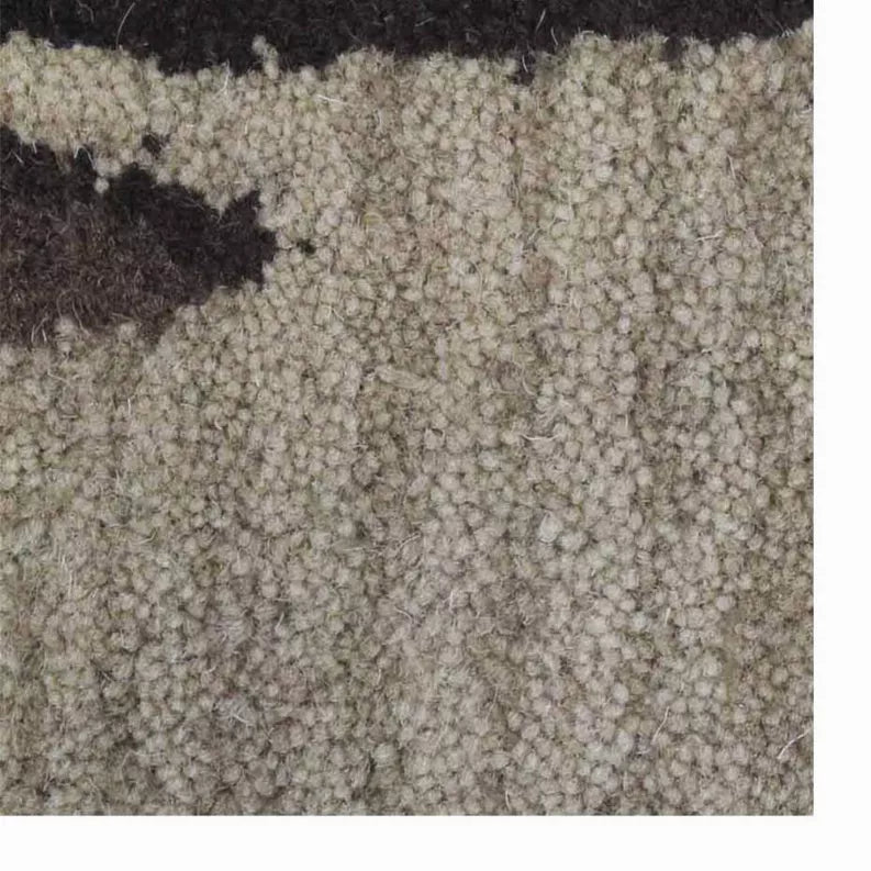 Close-up of textured beige wool rug with dark floral accent