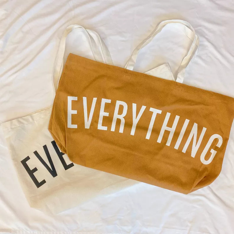 Tan canvas tote with "EVERYTHING" in white letters and short top handles.