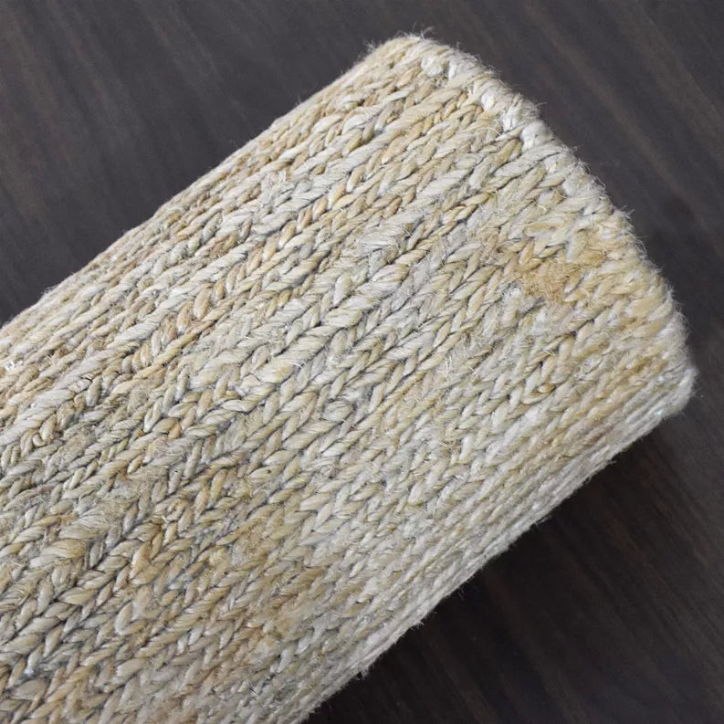 Textured jute area rug corner with braided weave, beige and gray tones