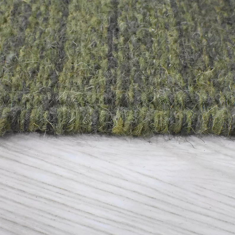 Olive green wool area rug corner, textured flat weave with visible fibers