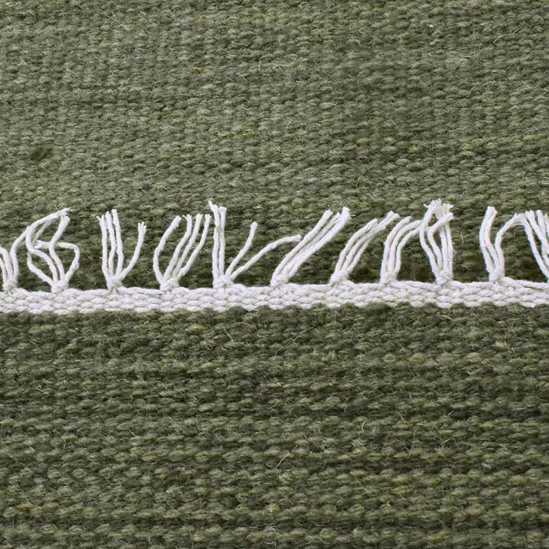 Olive green wool kilim rug with white fringe stripe across the edge