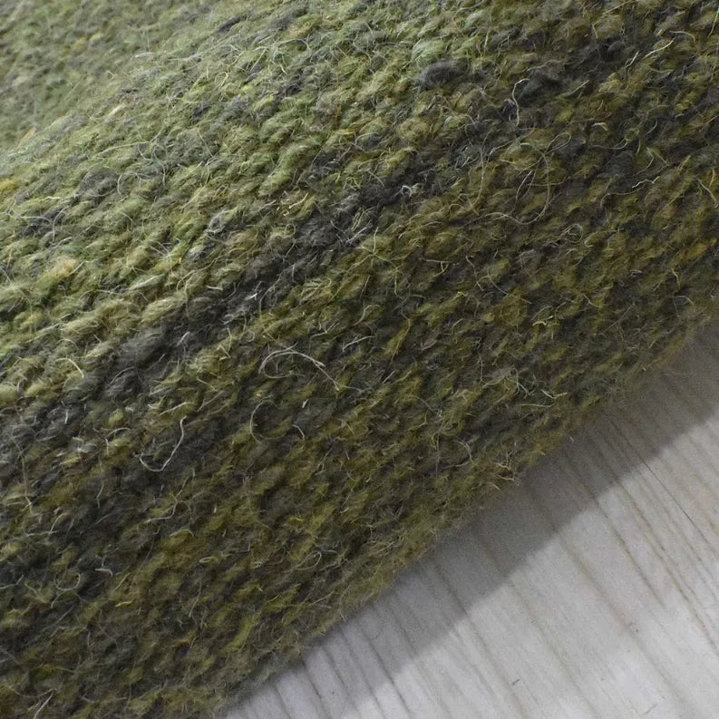 Olive green wool kilim rug corner with textured flat weave and dark diagonal shading