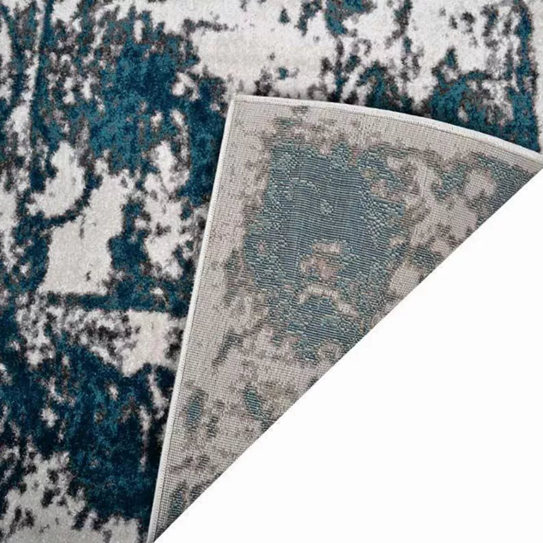 Abstract area rug corner detail with teal and off-white distressed pattern