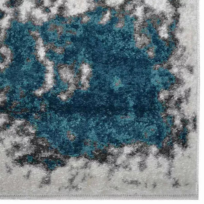 Abstract area rug close-up with teal center and light gray distressed texture