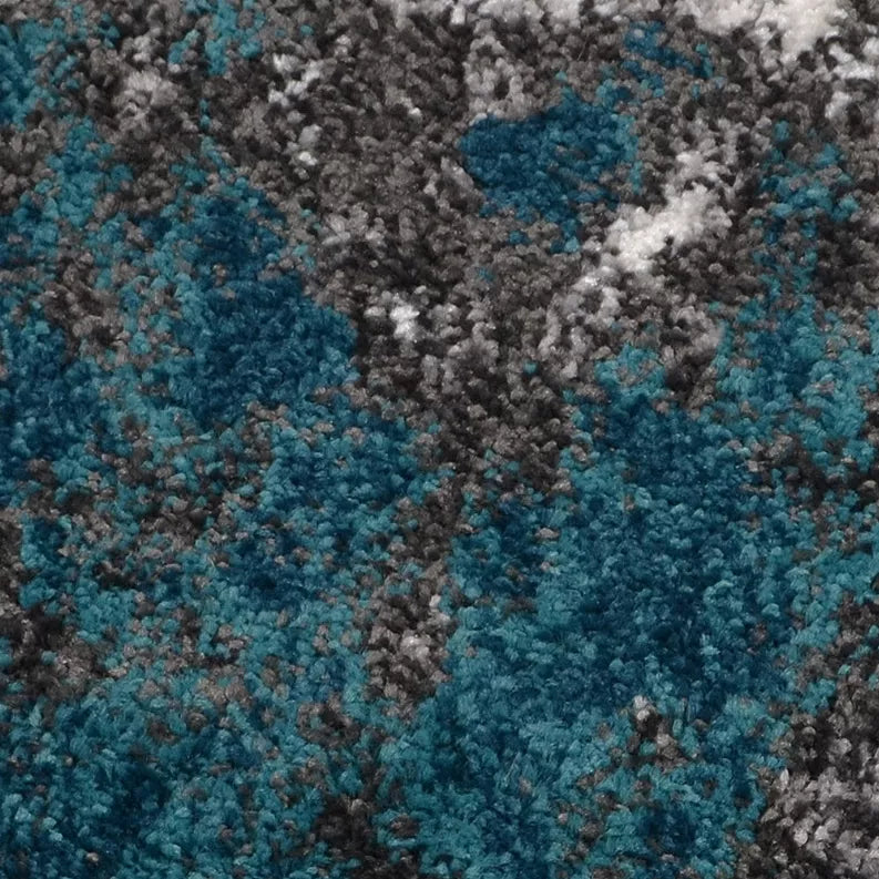 Close-up of rug fibers with teal blue, gray, and dark mottled abstract pattern