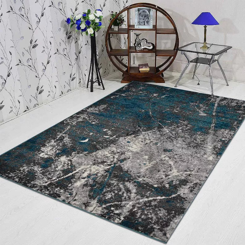 Abstract rectangular area rug with teal and gray distressed design on light floor