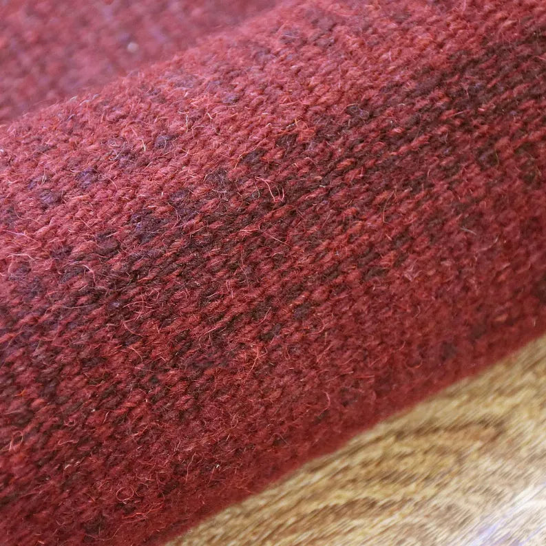 Burgundy wool rug with dense textured weave and angled corner view