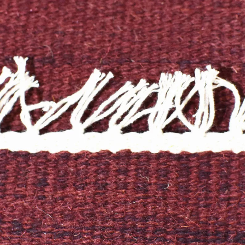 Burgundy flatweave rug with white distressed stripe across the surface