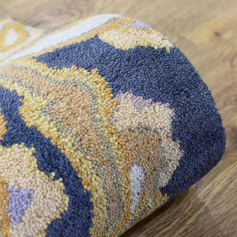 Hand-tufted wool area rug corner with cream, blue, yellow, and subtle purple floral motifs.
