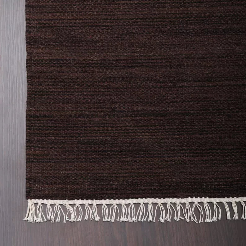 Dark brown rug border with cream fringe along the bottom edge; flat woven texture.