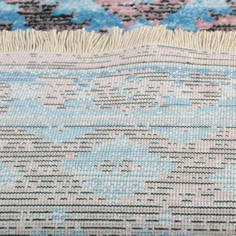 Rug weave close-up with light blue and pink pattern over white-and-charcoal yarns.