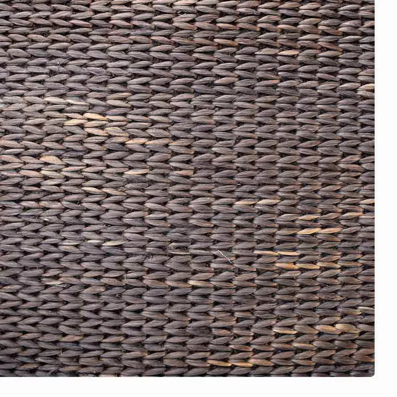 Hand-woven jute area rug close-up, dark charcoal with visible braided fiber texture