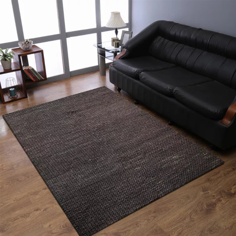 Hand-woven jute area rug, dark charcoal brown, solid rectangular weave on wood floor
