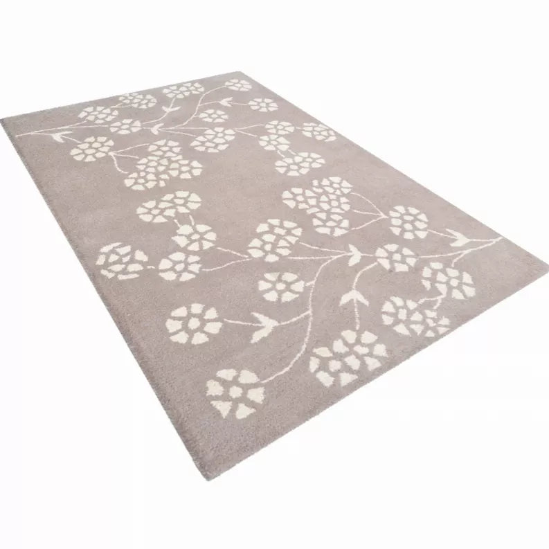 Taupe hand-tufted wool area rug with white floral vine motif, angled view