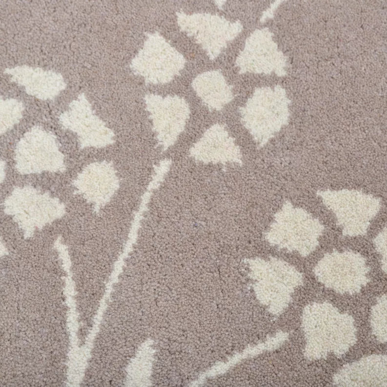 Taupe rug texture with white rosette and vine motifs, close-up detail