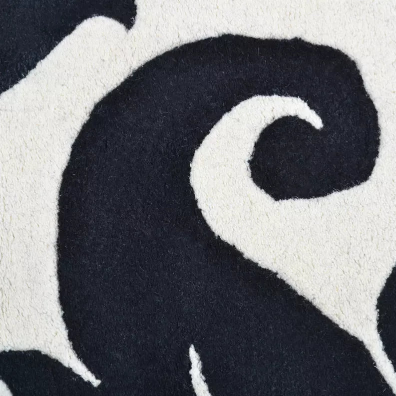 Black and ivory floral area rug with curving scrolling motif, close-up texture detail