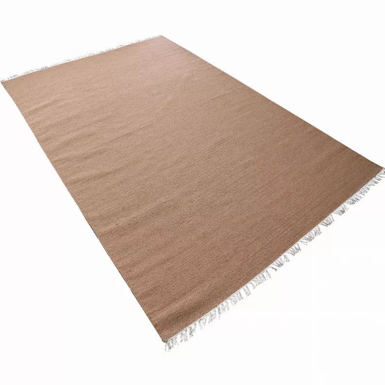 Tan flatweave Kilim wool rug with white fringe, angled view